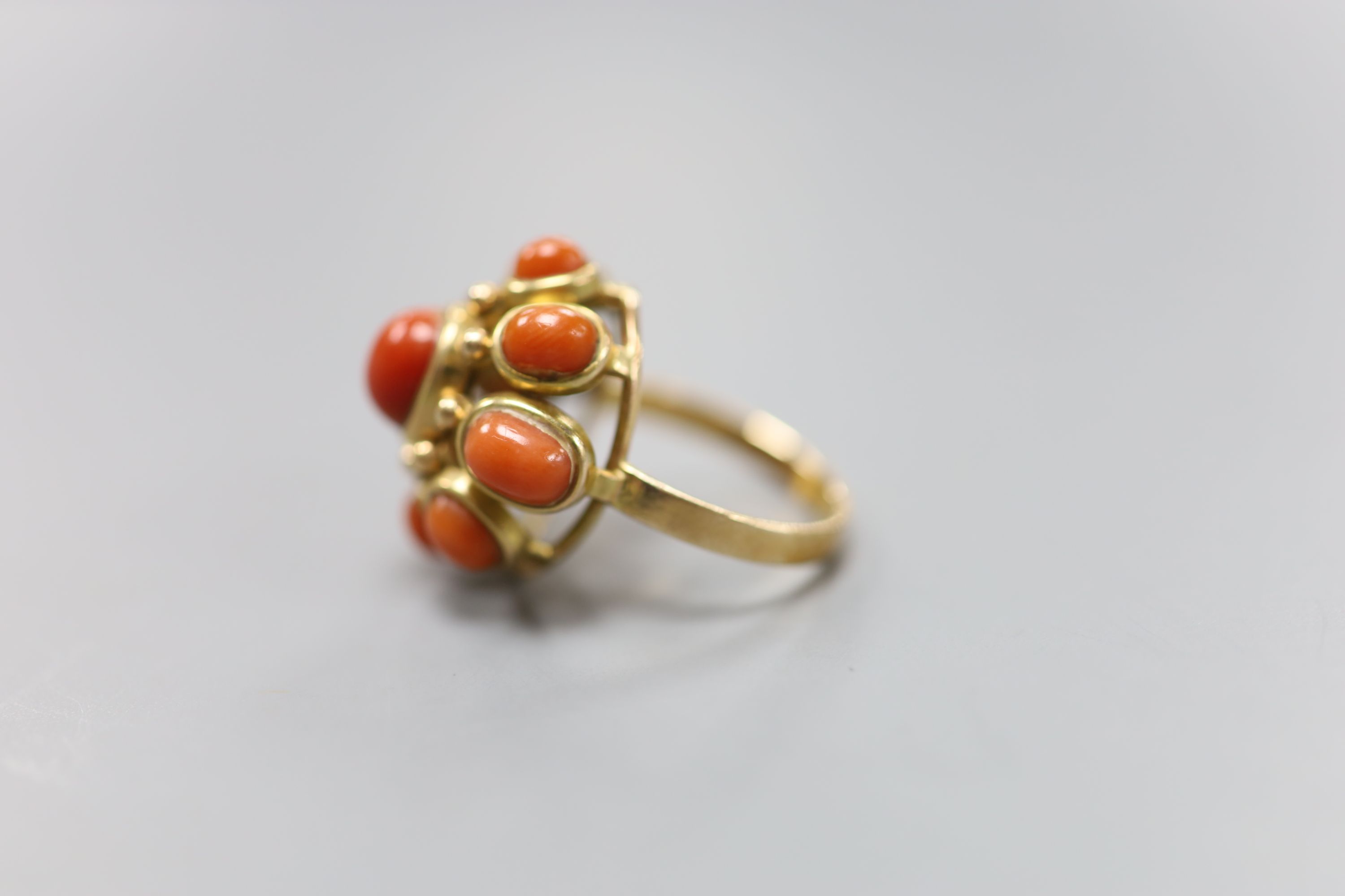 A yellow metal and nine stone coral bead cluster set dress ring, size O, gross 9.1 grams.